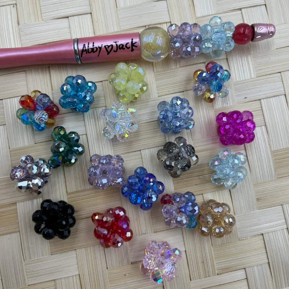 16MM crystal cluster ball fancy beads in assorted colors including pink, blue, black, red, purple, and clear displayed on a woven surface next to a beadable pen
