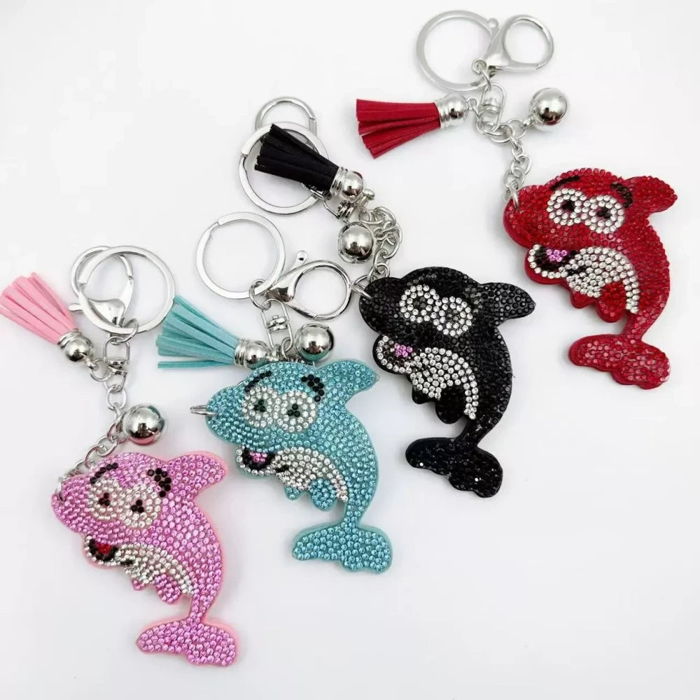 Four rhinestone dolphin charms in pink, aqua, black, and red with silver-tone rings, bells, and tassels on a white background. - Random Mixed