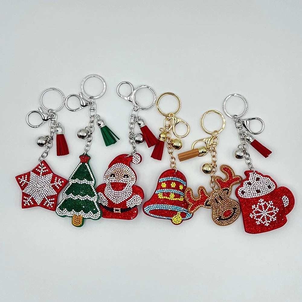 Set of 6 Christmas diamond painting keychains featuring Santa Claus, reindeer, Christmas tree, star, jingle bells, and mitten designs with tassels and jingle bell charms on silver and gold rings.