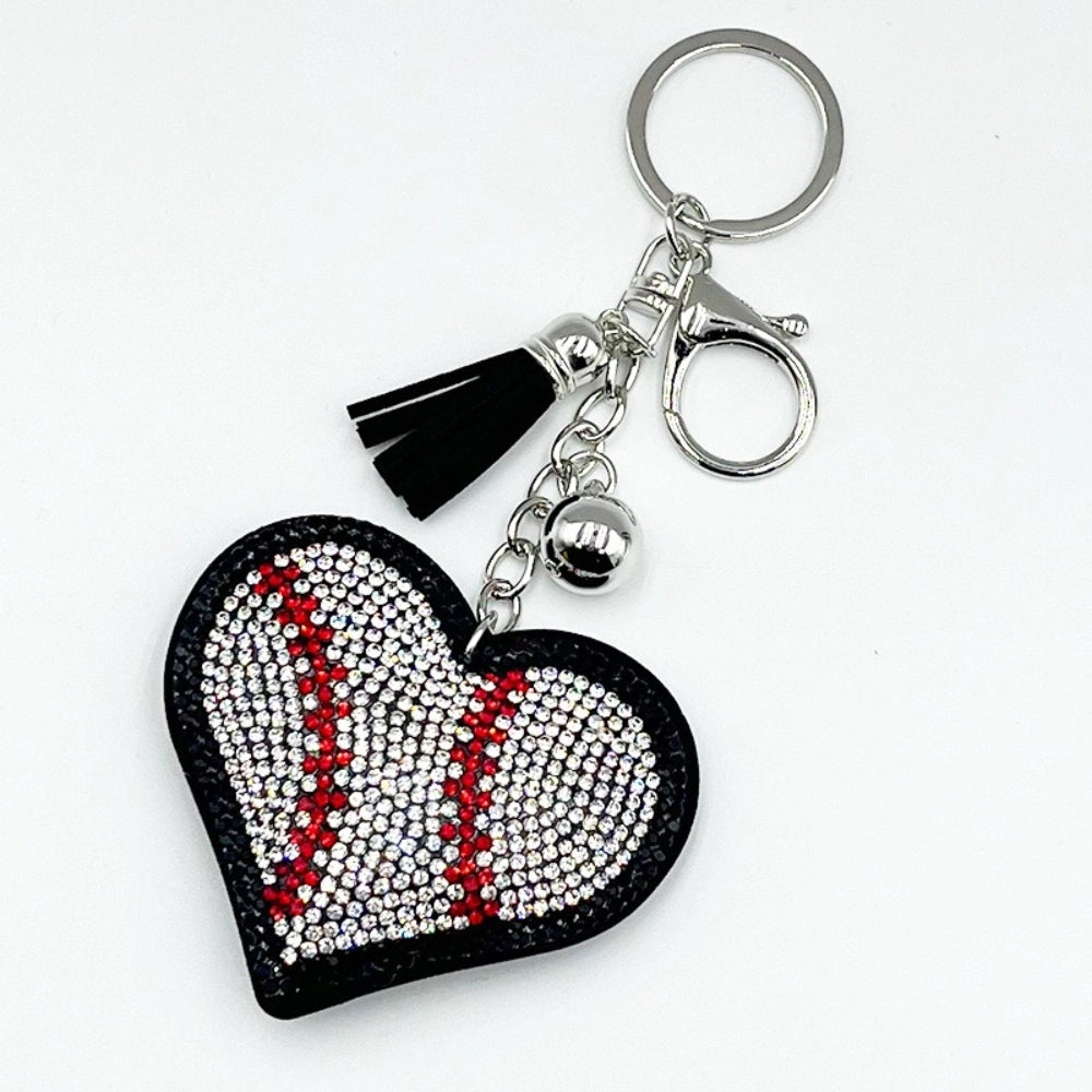 Crystal rhinestone baseball heart keychain charm with black leather backing, red and clear gems, black tassel, silver bell, and lobster clasp on white background.