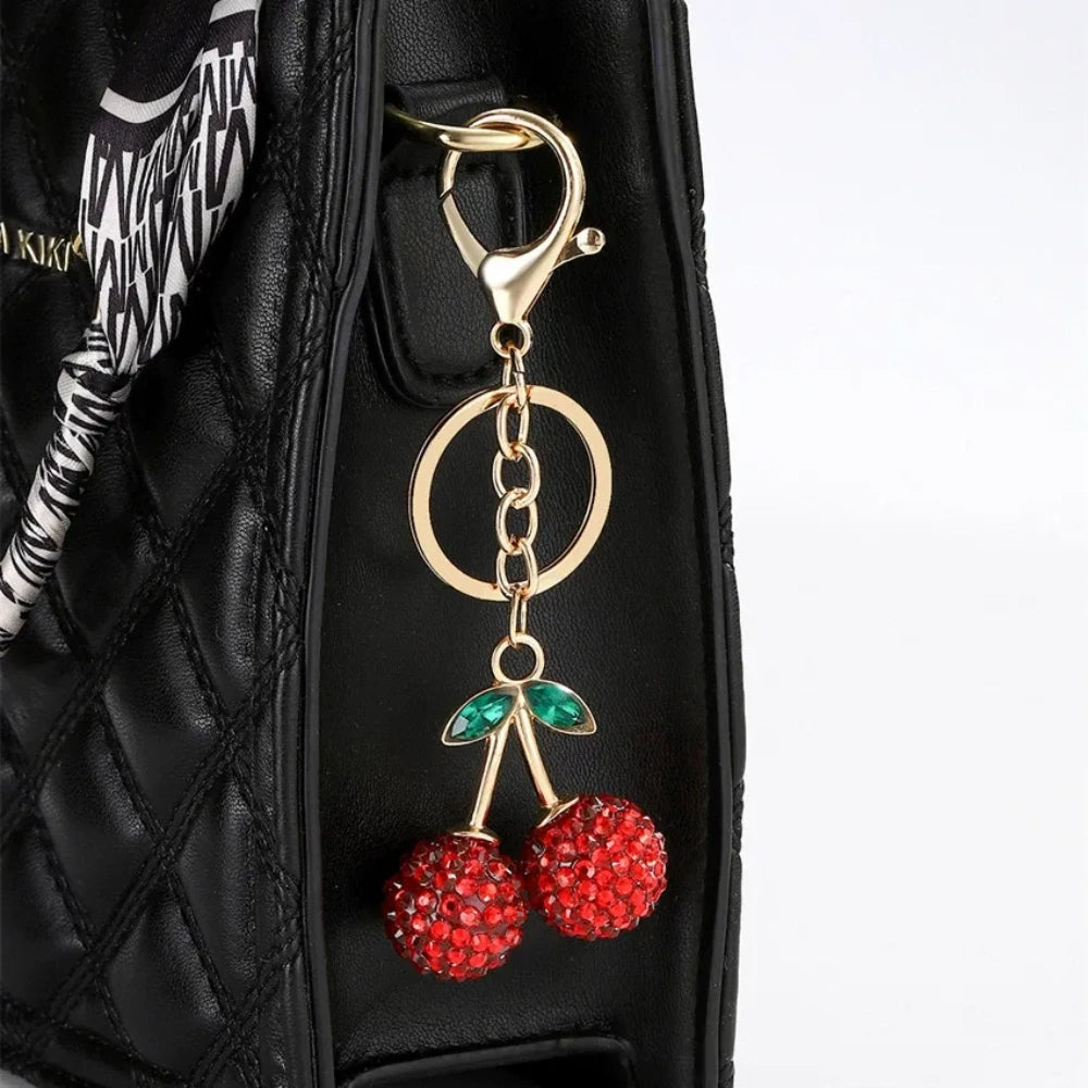 Three crystal rhinestone cherry charm keychains in pink mixed, solid pink, and red, with gold tone stems and green leaf accents on a white background. - Red