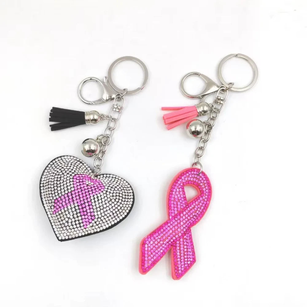 Two pink ribbon awareness rhinestone keychain charms on a white background, including a silver heart with pink ribbon and a pink awareness ribbon charm with tassels. - Random Mixed