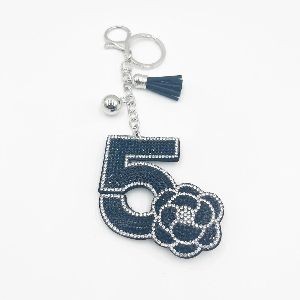 Navy blue rhinestone Number 5 camellia flower keychain charm with silver crystal border, tassel and lobster clasp on white background.