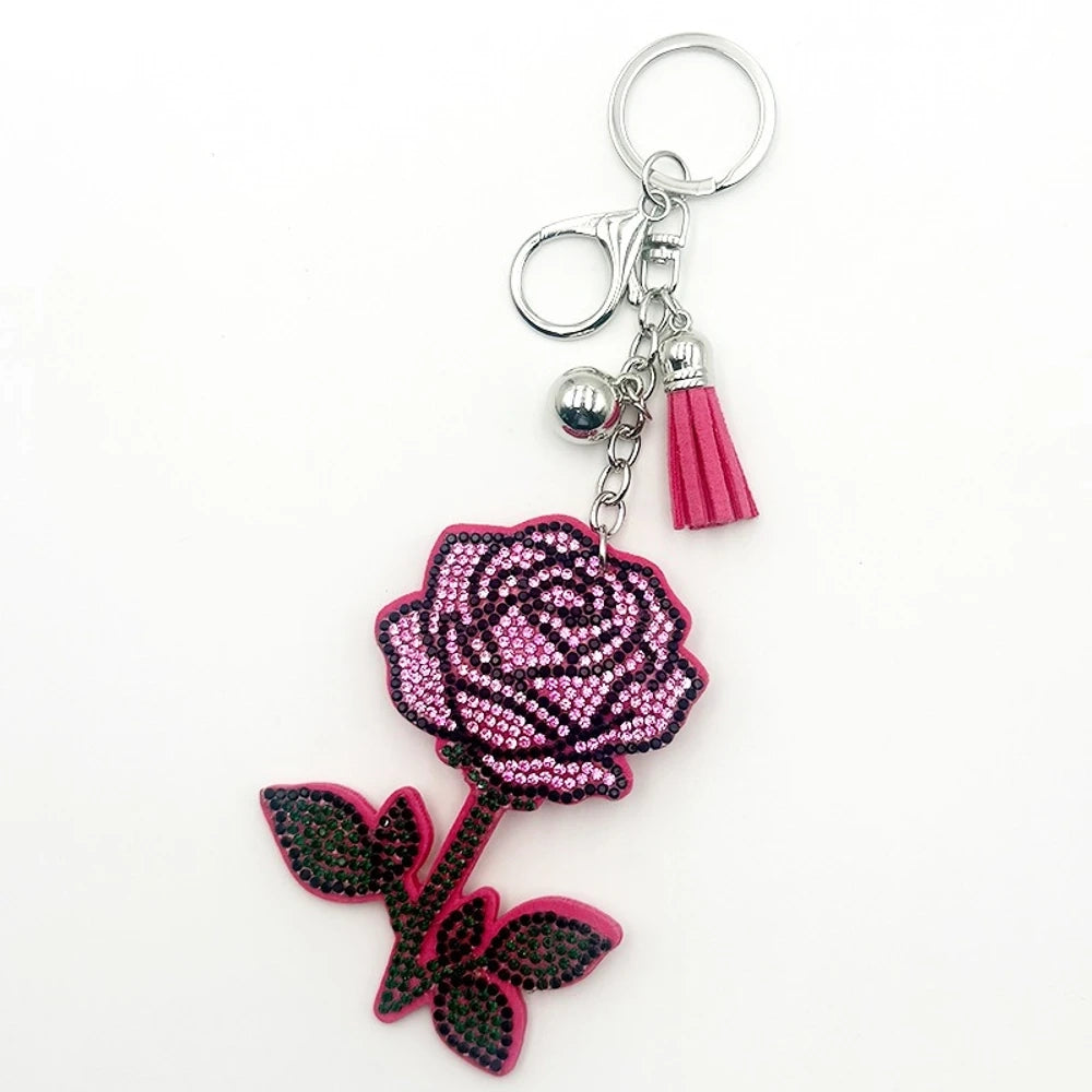 Sparkling red and black rhinestone rose flower keychain charm with gold ring, lobster clasp, gold bead, and red tassel accent on white background. - Pink