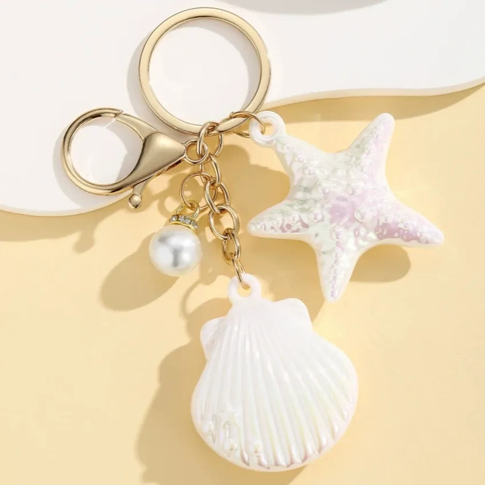 Six colorful resin ocean shell and starfish keychain charms with pearl beads in pink, white, purple, blue, iridescent, and hot pink, displayed on a yellow background. - 4