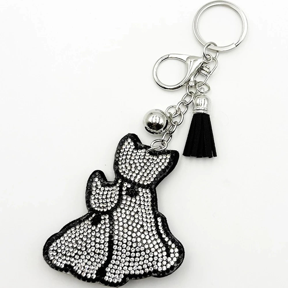 Crystal rhinestone embellished cat shaped keychain charm with black suede tassel and silver lobster clasp hardware on white background