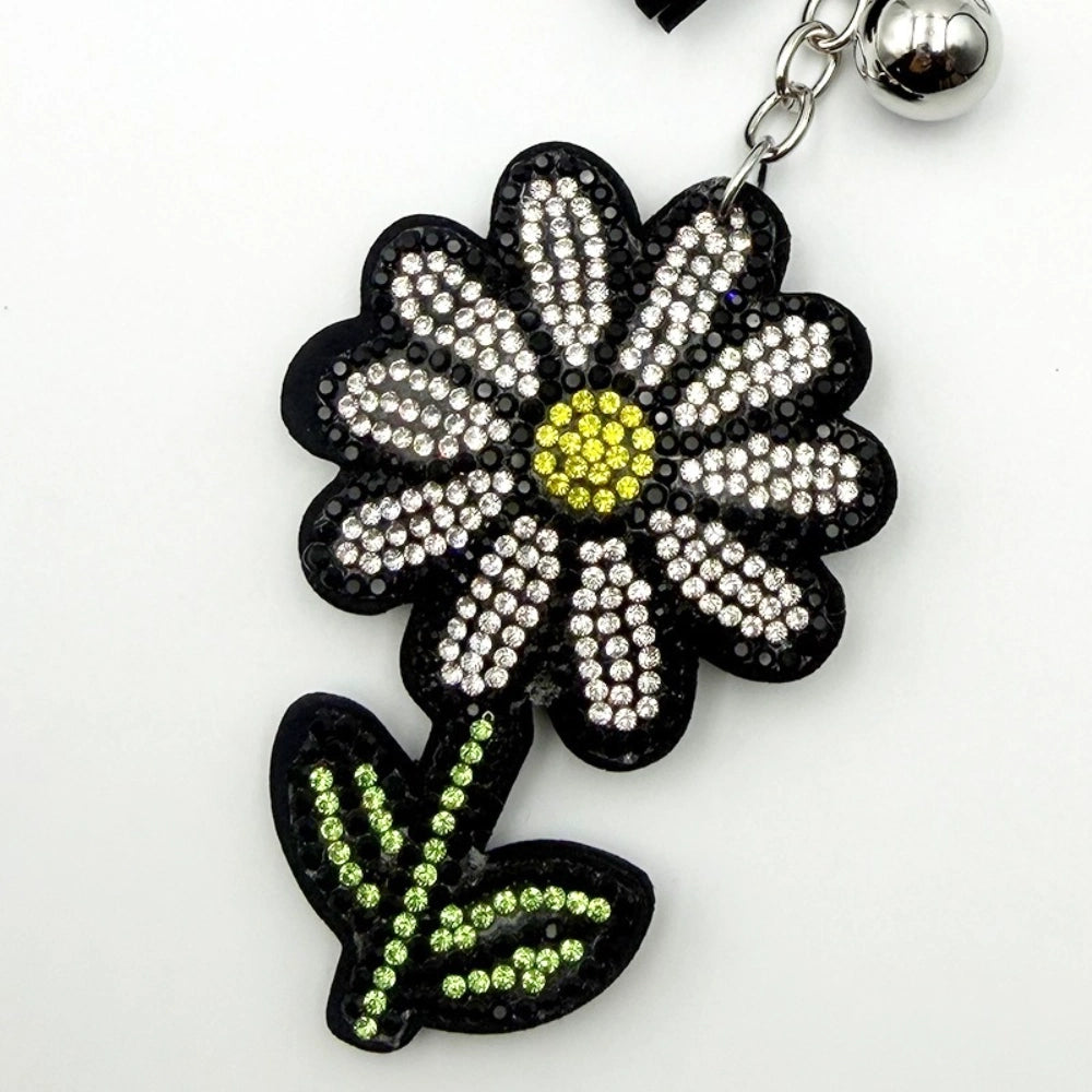 Rhinestone crystal daisy flower keychain charm pendant with clear crystal petals, yellow center, green stem and leaves on black base with silver chain