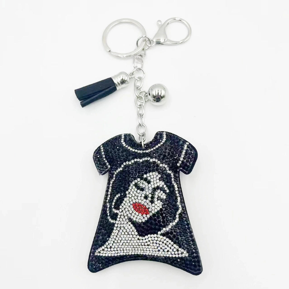 Black rhinestone-encrusted ghost face t-shirt shaped keychain charm with silver lobster clasp, chain, ball charm, and navy blue tassel accent on white background.