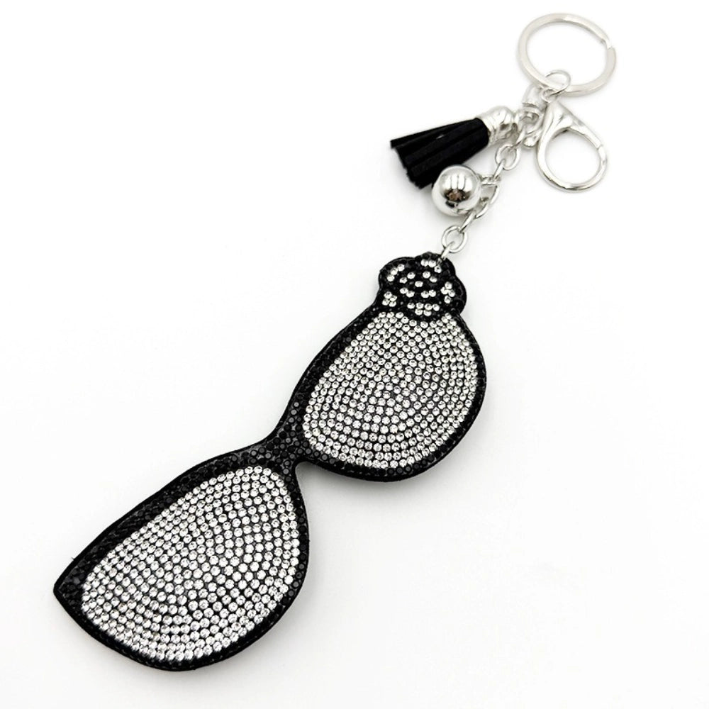 Rhinestone-covered sunglasses keychain charm with black frame, crystal clear stones, black tassel, and silver lobster clasp hardware on white background.