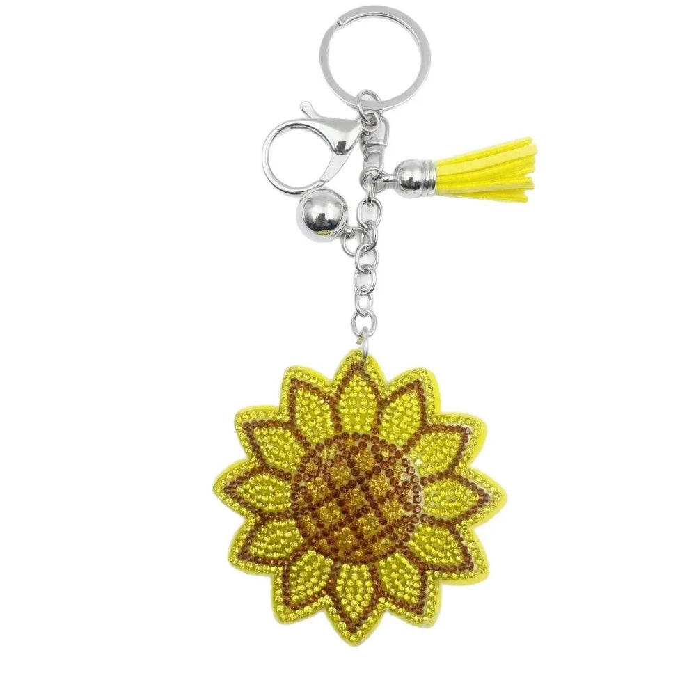 Yellow sunflower rhinestone fancy bead charm with silver keyring, clasp, bell, and tassel on a white background