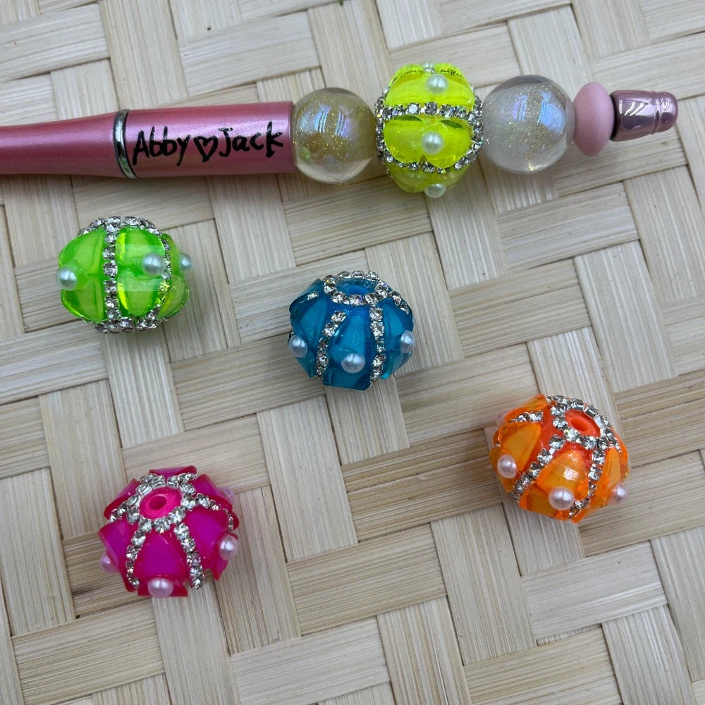 Assorted neon translucent acrylic cage beads with rhinestone bands and pearl accents, shown loose and on a beadable pen