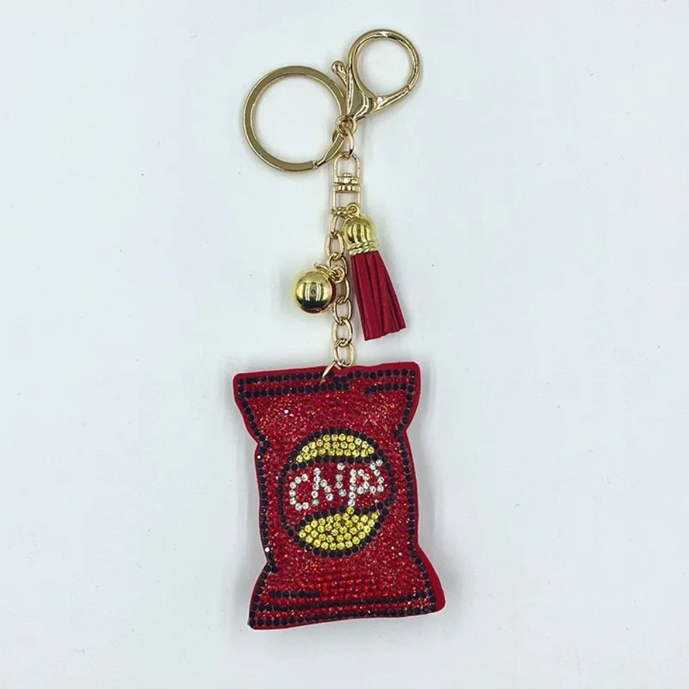 Red chip bag shaped rhinestone fancy bead charm with gold hardware, bell, and tassel on a white background