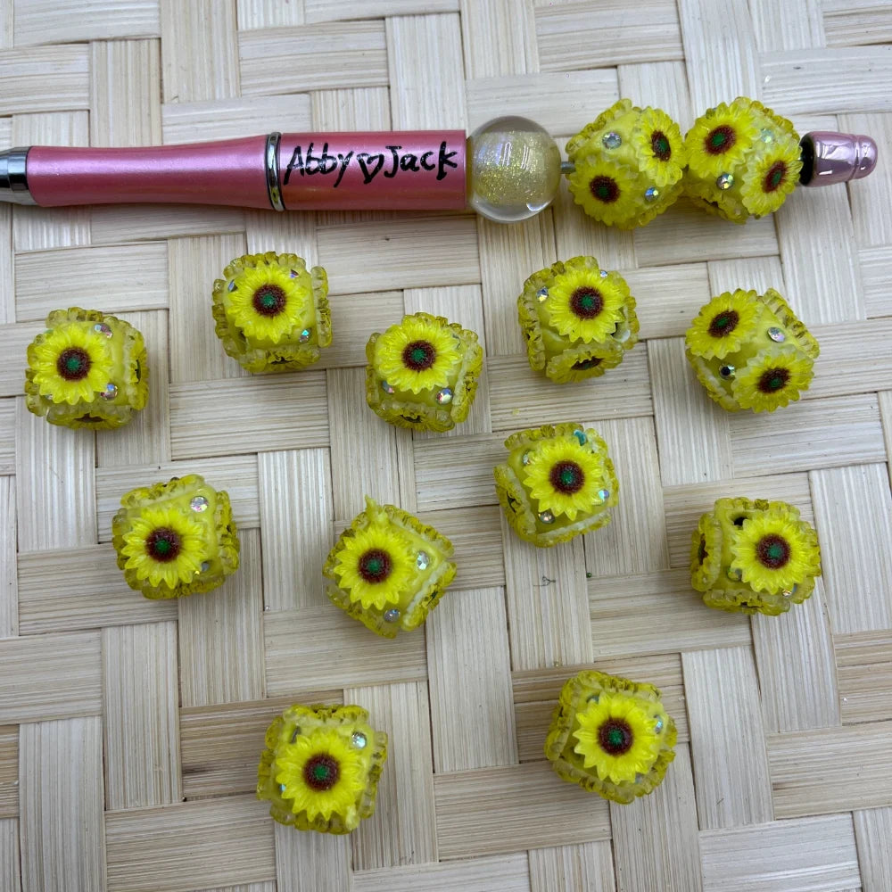 Yellow sunflower cube resin beads with rhinestone accents displayed beside a beadable pen
