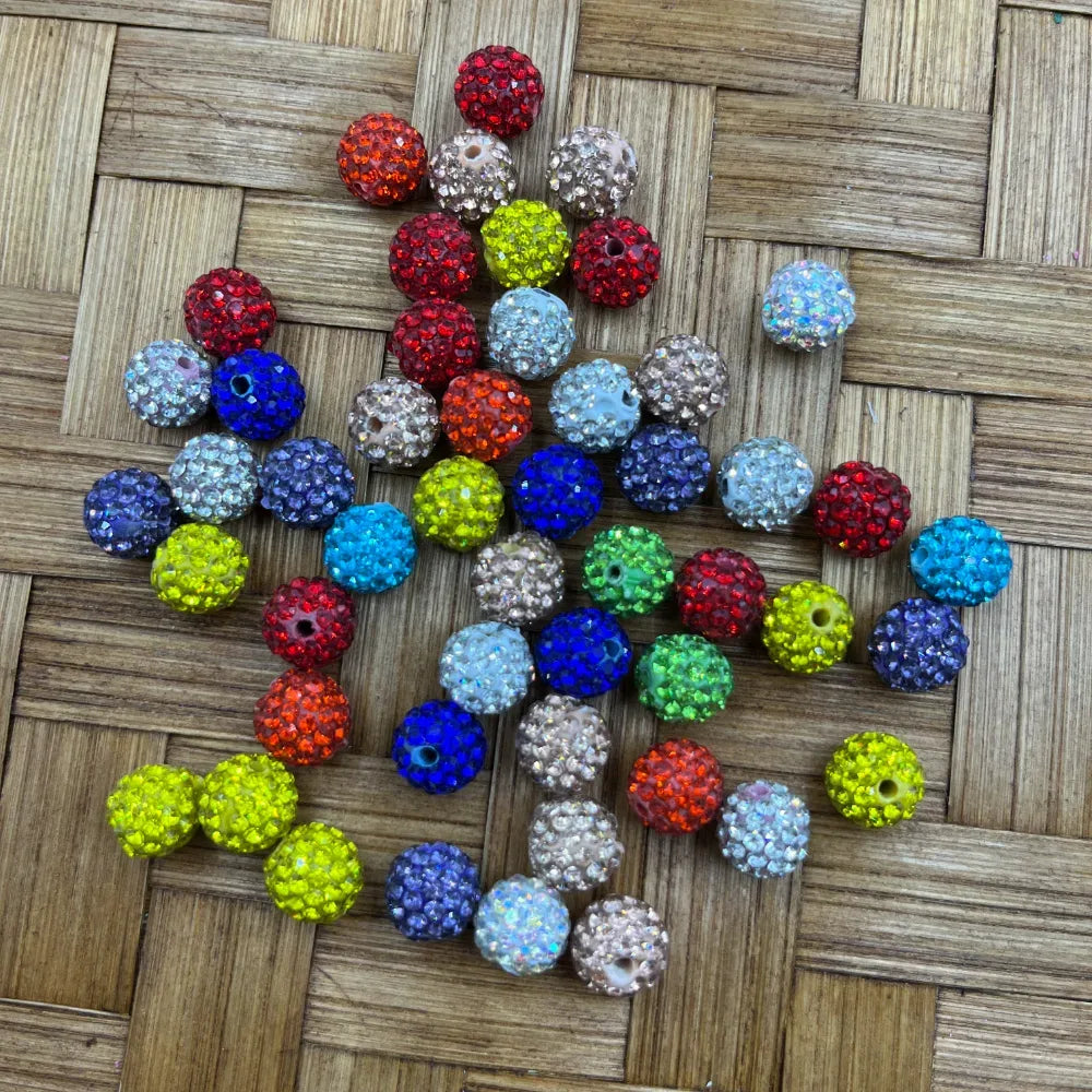 10MM mixed color clay rhinestone beads in red, blue, green, orange, yellow, clear, and purple on a woven bamboo surface for DIY jewelry making and beadable pens.