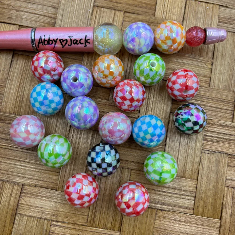 16MM iridescent checkered acrylic beads in assorted colors including red, purple, orange, green, blue, pink, and black and white checker patterns displayed on a woven surface next to a beadable pen