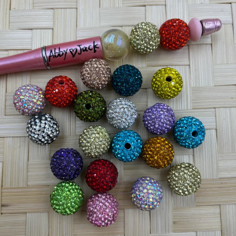 Assorted 16MM multicolor round pave clay rhinestone beads shown with a beadable pen