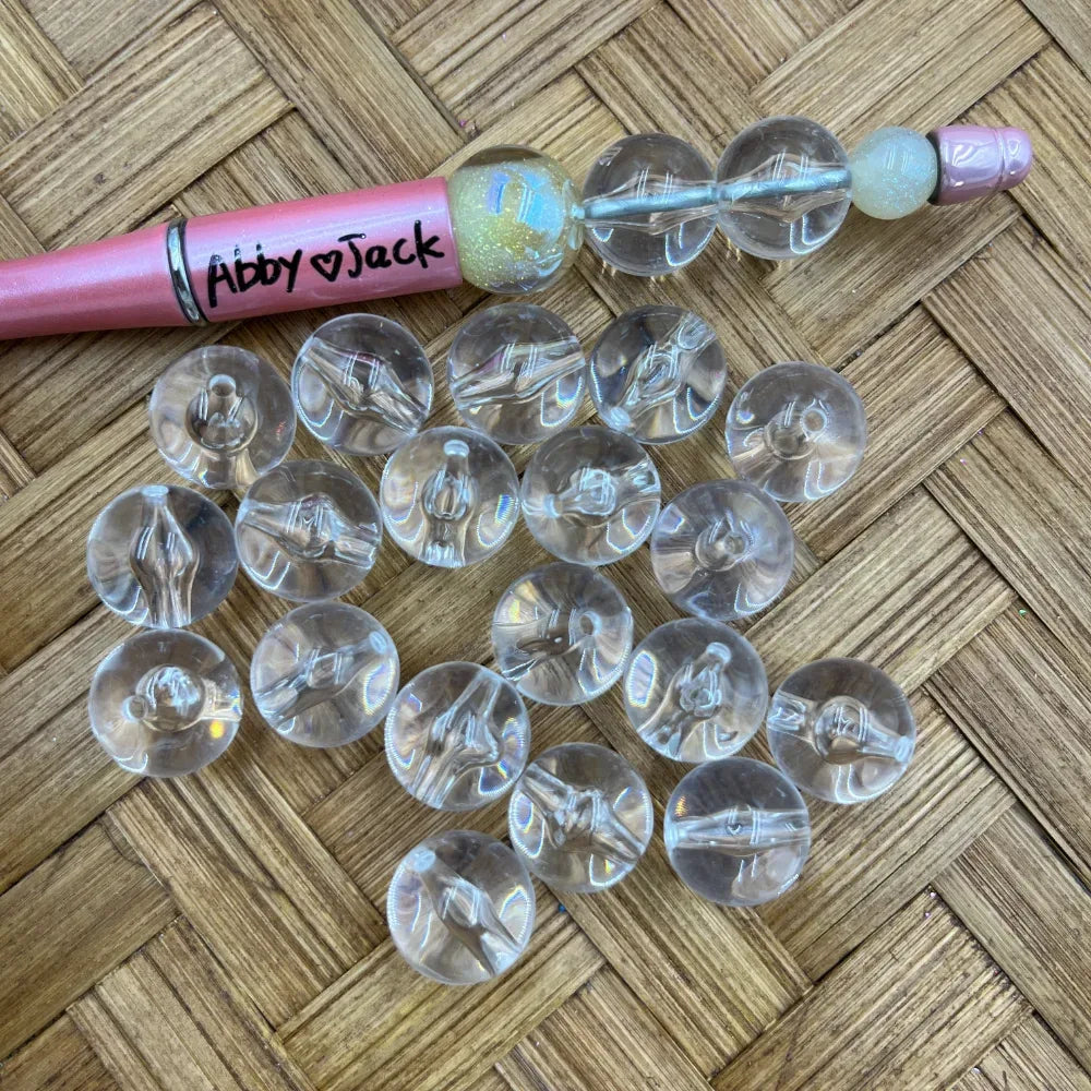 16MM clear transparent round acrylic beads with inner stem detail shown loose on wicker surface next to a pink beadable pen labeled Abby Jack, used for DIY jewelry making and beadable pens.