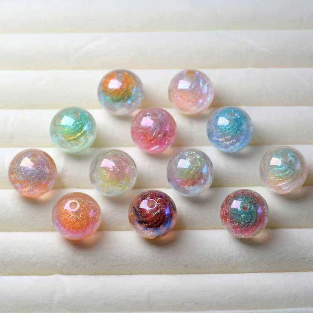 16MM round galaxy glitter acrylic beads in assorted iridescent swirl colors including pink, teal, orange, purple, and clear with holographic shimmer finish, displayed on white ridged background.