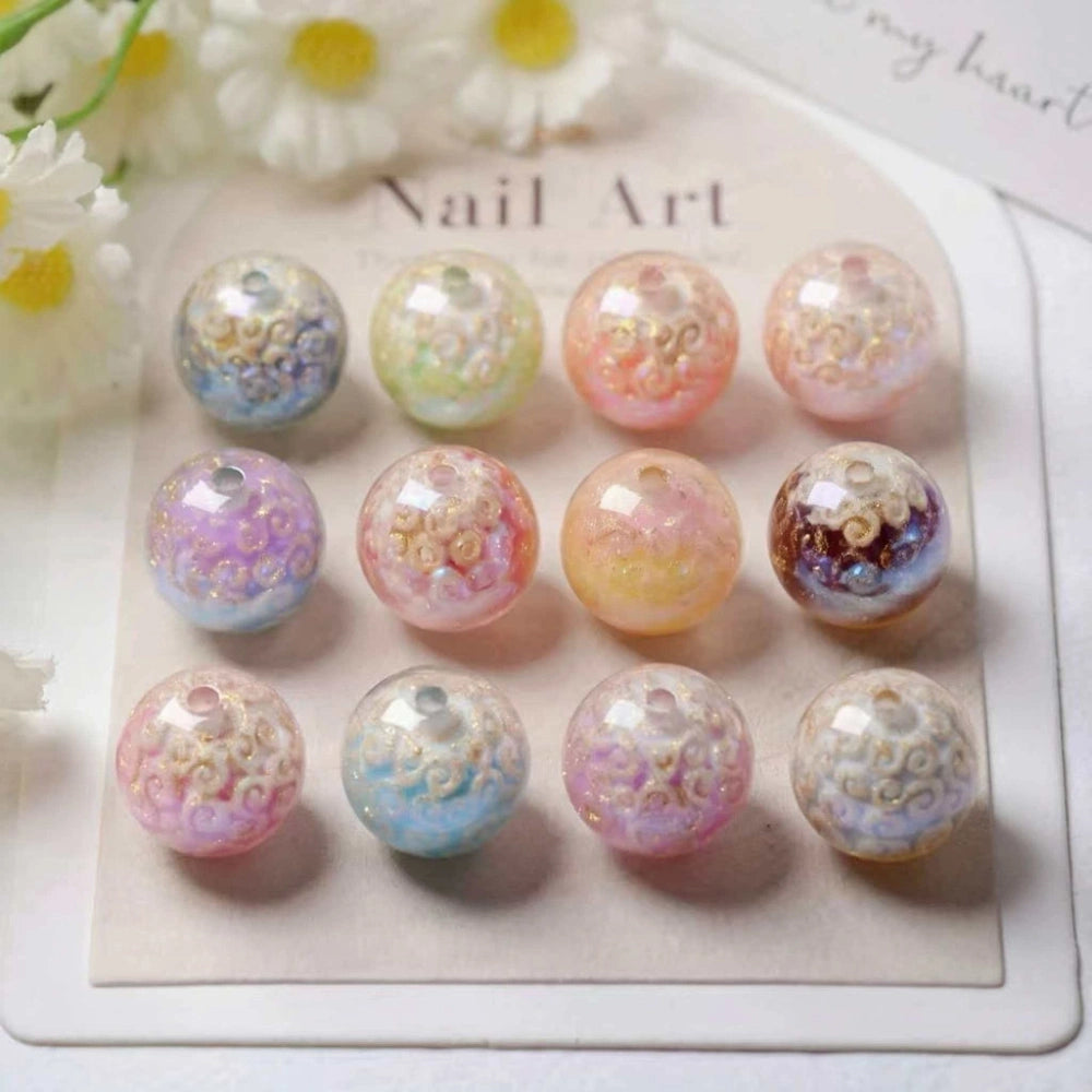 12 pastel iridescent cloud swirl acrylic beads in assorted colors including pink, purple, blue, orange, and brown displayed on a nail art card with daisy flowers in background.