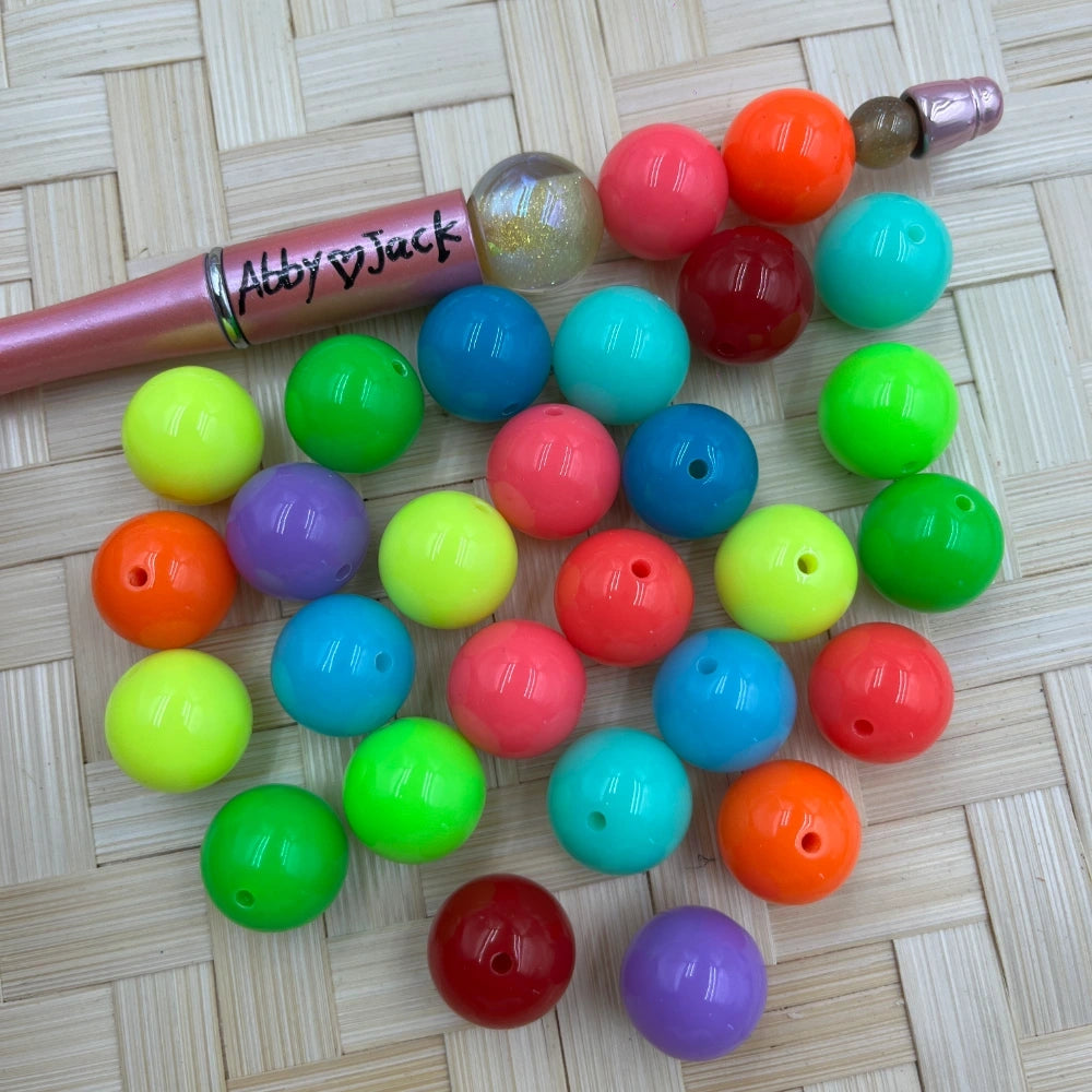16MM neon bright solid acrylic beads in mixed colors including green, orange, red, teal, yellow, purple, and blue scattered on a woven surface next to a beadable pen.
