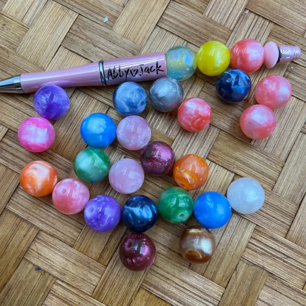 Assorted 16MM pearlescent marble acrylic beads in multiple colors including pink, blue, purple, orange, green, and red displayed on a woven surface next to a beadable pen.