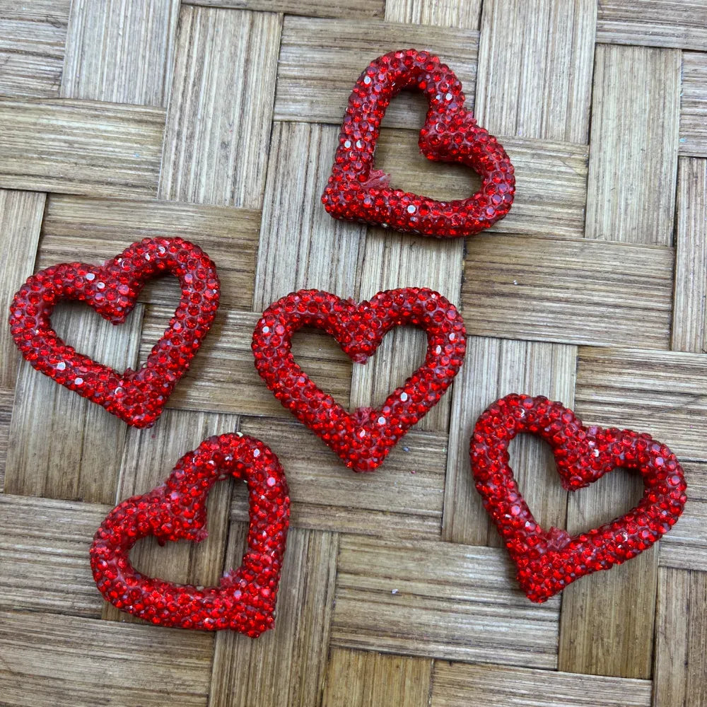 16MM red crystal rhinestone open heart shaped beads arranged on a woven bamboo surface, sparkling faceted rhinestone embellishments for DIY jewelry making and beadable pens.