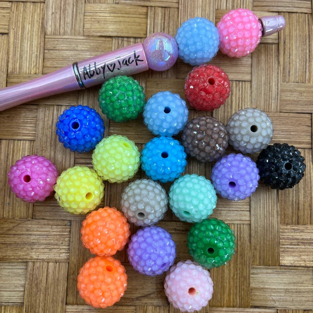16MM colorful rhinestone bubble textured acrylic beads in assorted colors including pink, blue, green, yellow, orange, purple, black, and more, displayed next to a beadable pen on a woven surface.