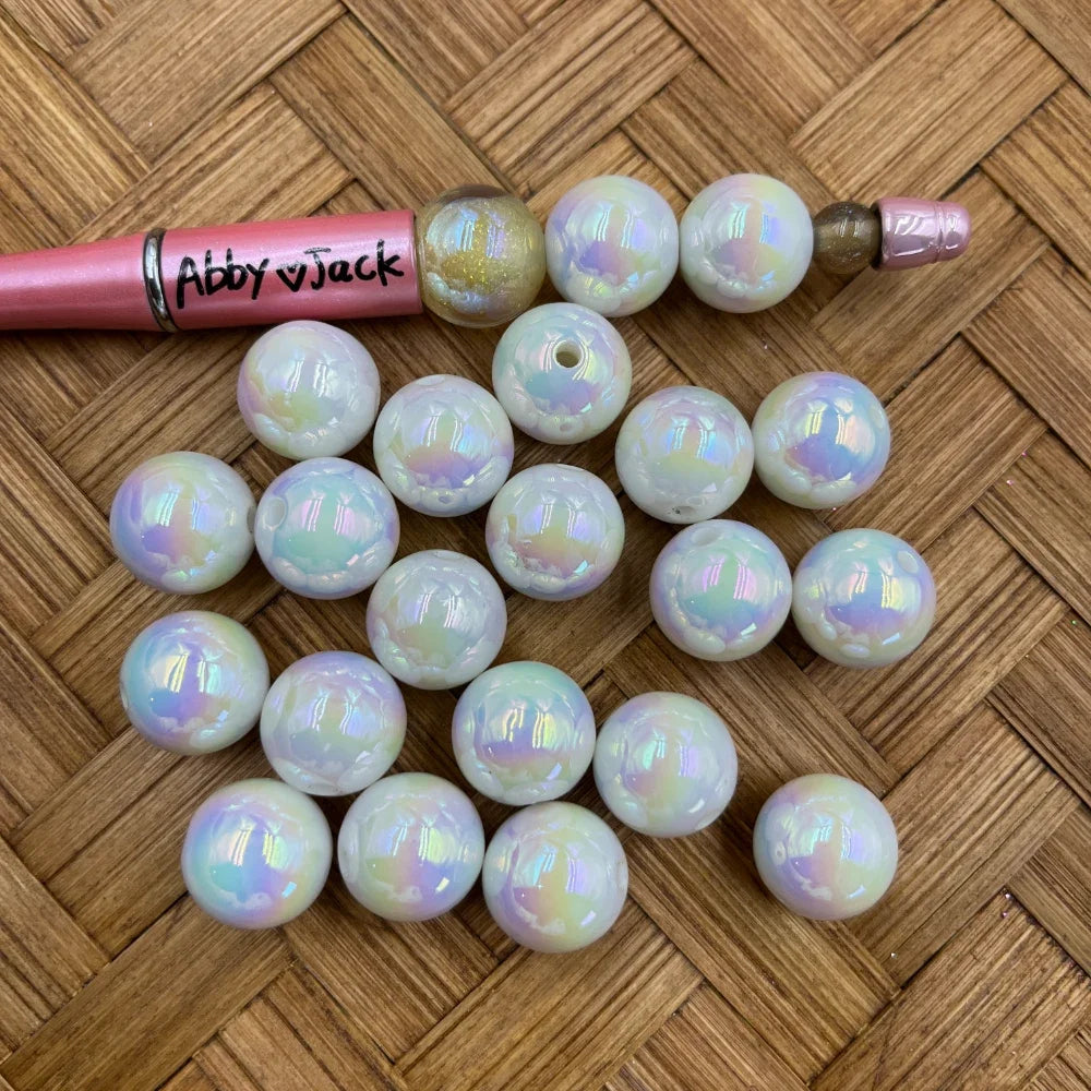 16MM white iridescent AB acrylic round beads with rainbow aurora shimmer finish displayed next to a beadable pen on a wicker surface