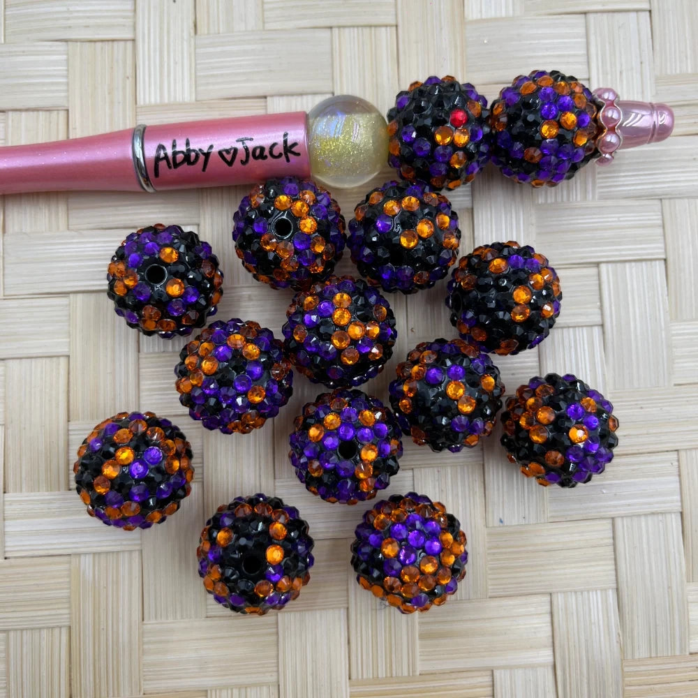 20MM Halloween rhinestone beads in black, orange, and purple crystal pattern displayed on woven surface with a beadable pen.