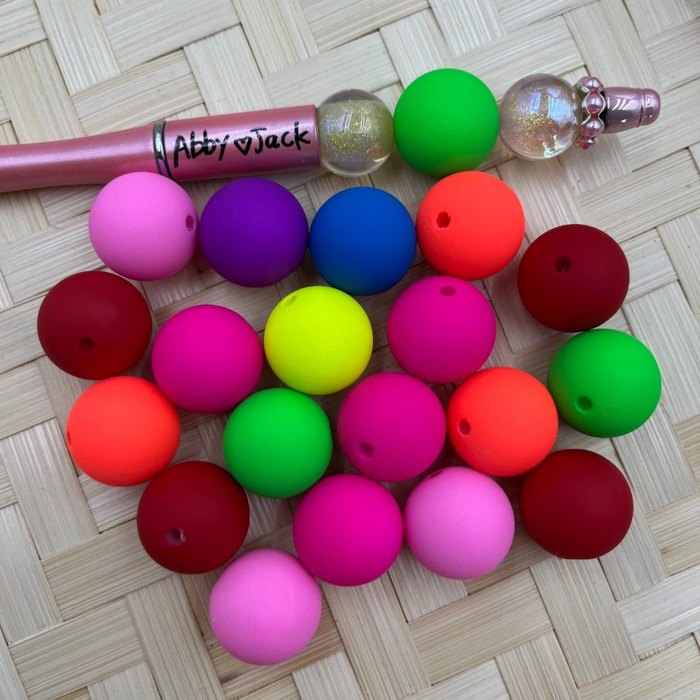 20MM neon and bright solid matte acrylic beads in assorted colors including hot pink, green, orange, red, purple, blue, and yellow, displayed next to a beadable pen on a woven surface.
