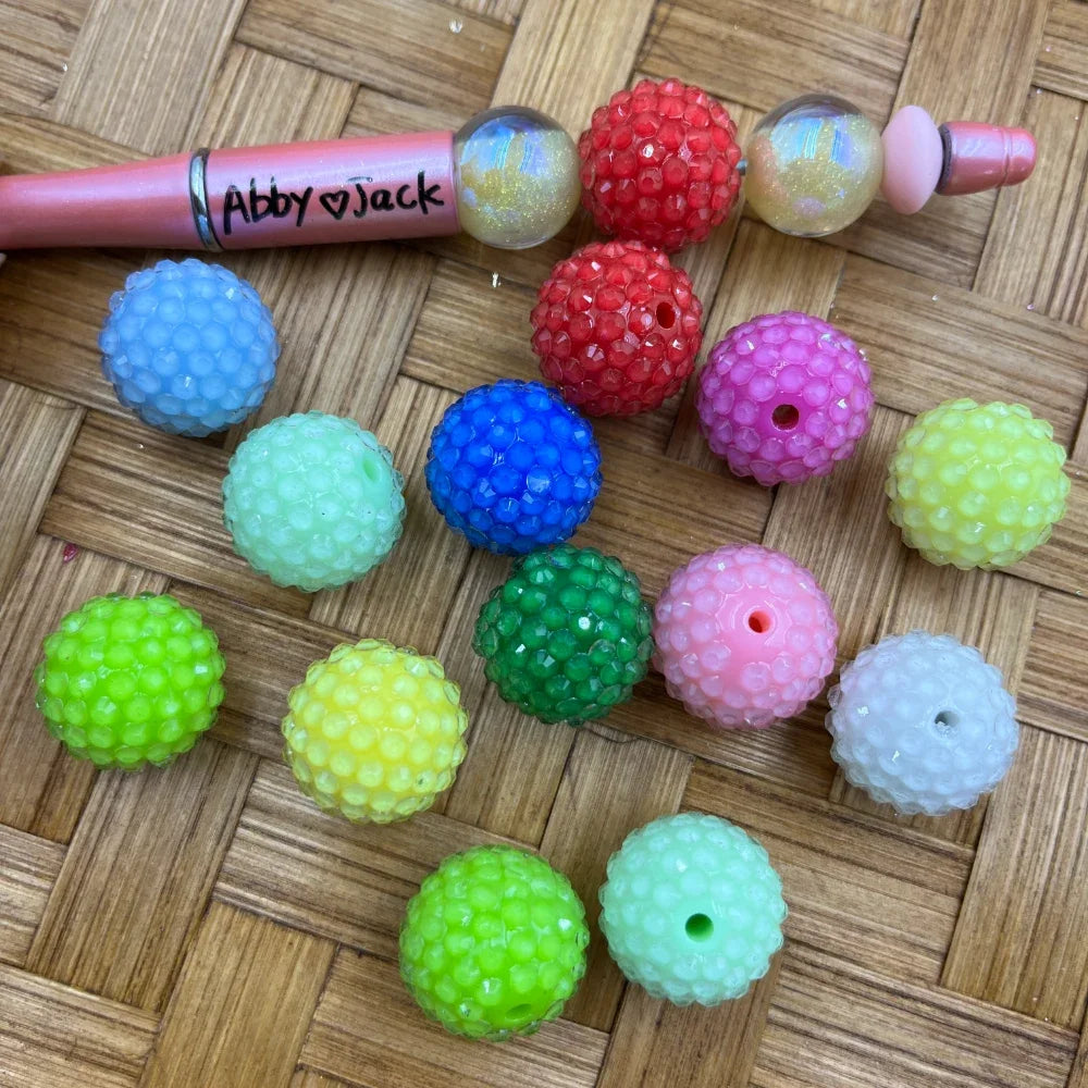 20MM raspberry textured bumpy acrylic beads in assorted colors including red, blue, green, pink, yellow, and lime green displayed on a wicker surface next to a beadable pen.