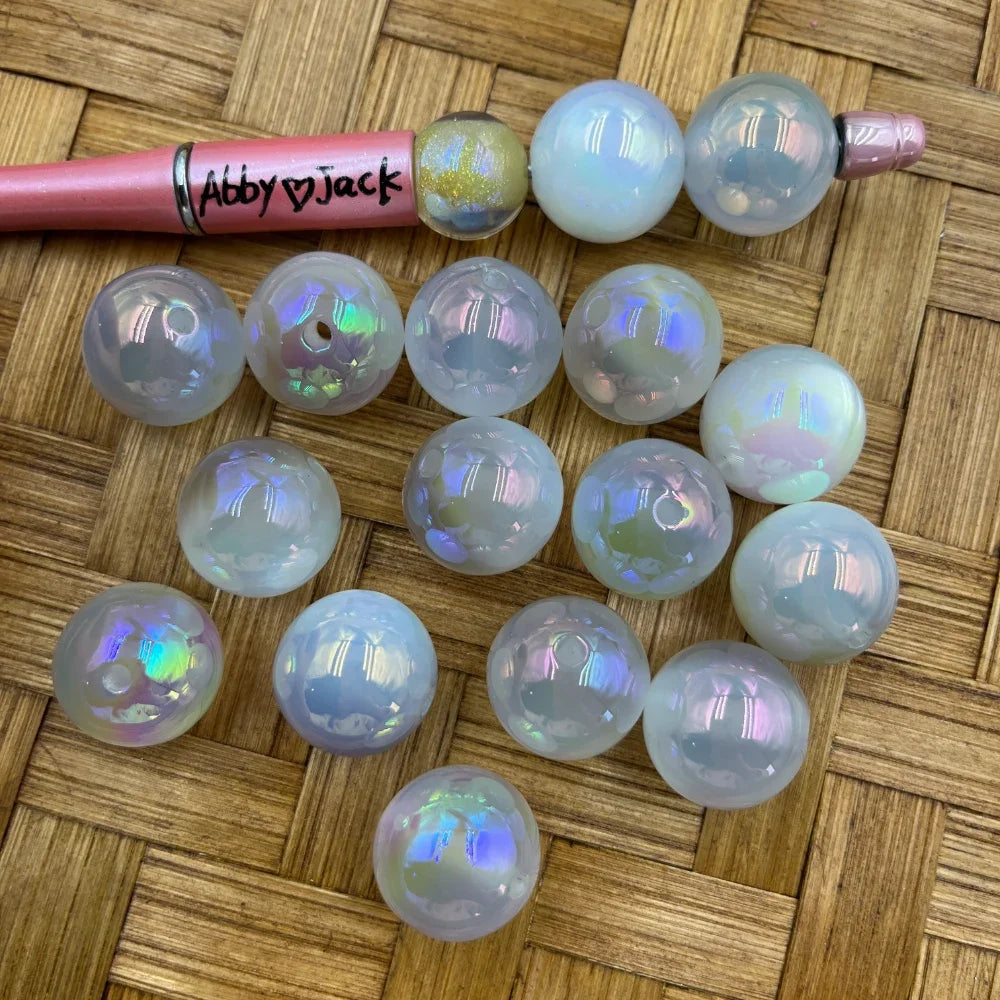 20MM white iridescent AB acrylic beads with aurora borealis rainbow shimmer finish displayed on woven surface next to a pink beadable pen, used for DIY jewelry making, keychains, and bracelets.
