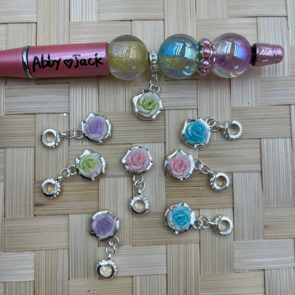 Set of pastel rose resin and silver-tone alloy bail beads in pink, blue, green, and purple shown with a beadable pen sample