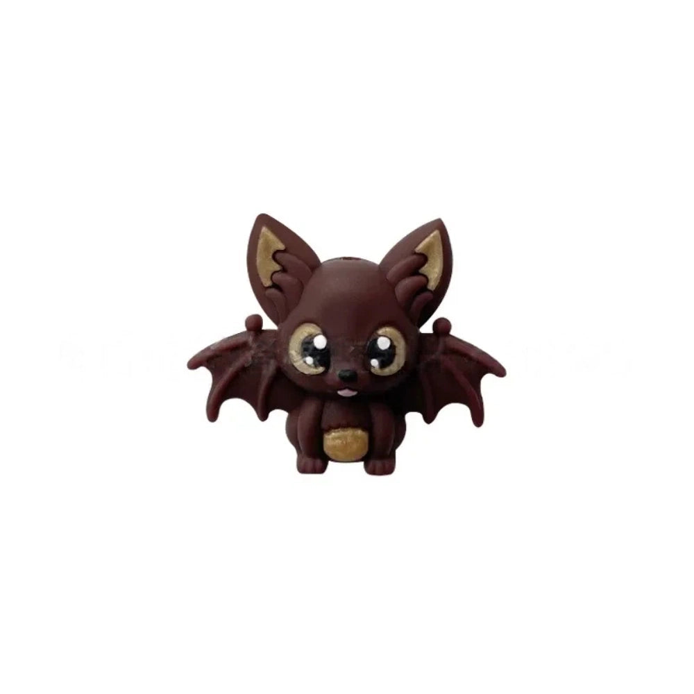 Six colorful 3D silicone baby bat focal beads in black, purple, gray, white, brown, and copper displayed on a wooden tray against a pink background. - Coffee