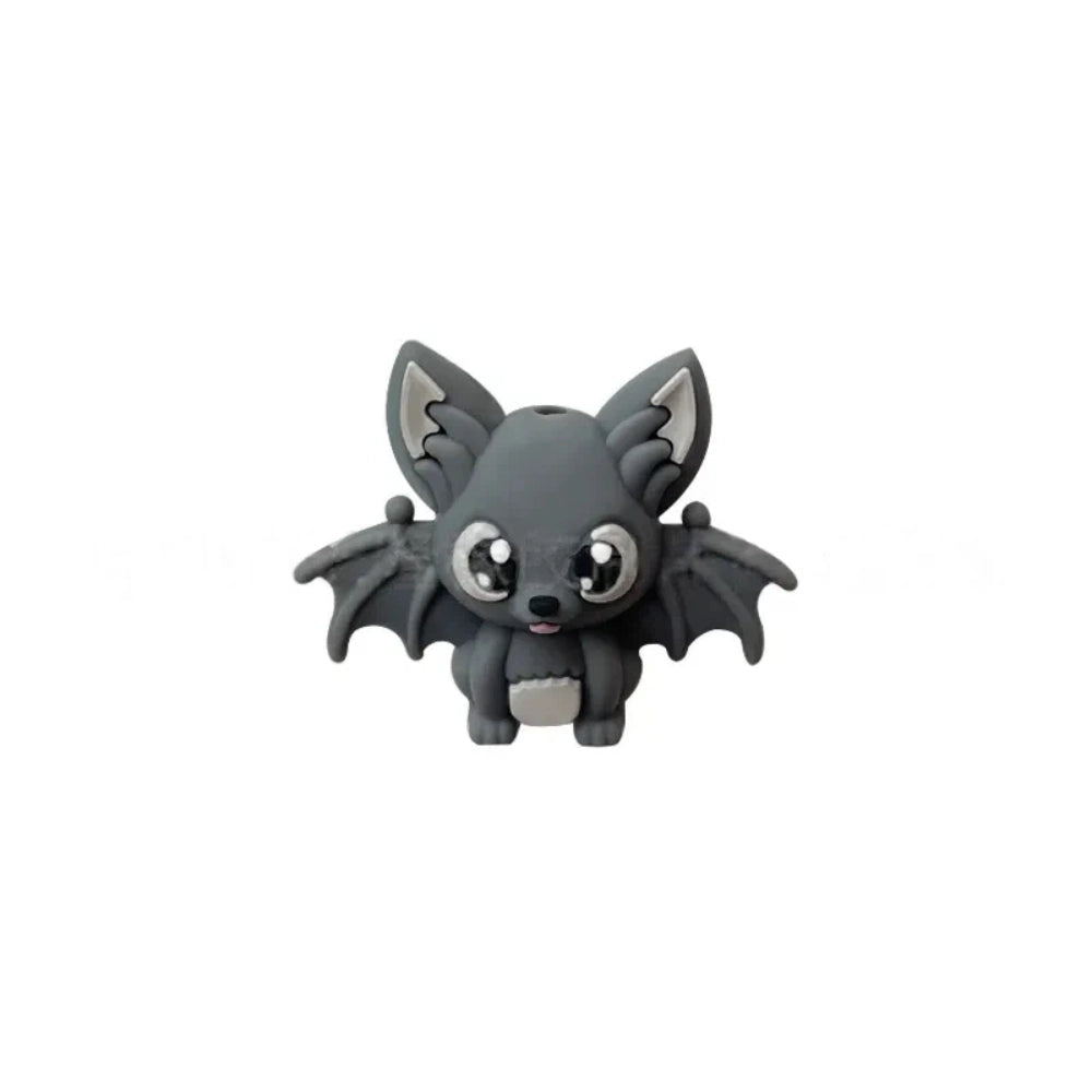 Six colorful 3D silicone baby bat focal beads in black, purple, gray, white, brown, and copper displayed on a wooden tray against a pink background. - Dark Gray
