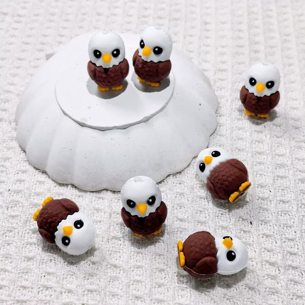 Cute 3D bald eagle silicone focal beads with white head, brown body, and yellow beak, displayed on a white surface — perfect for beadable pens, keychains, and badge reels.