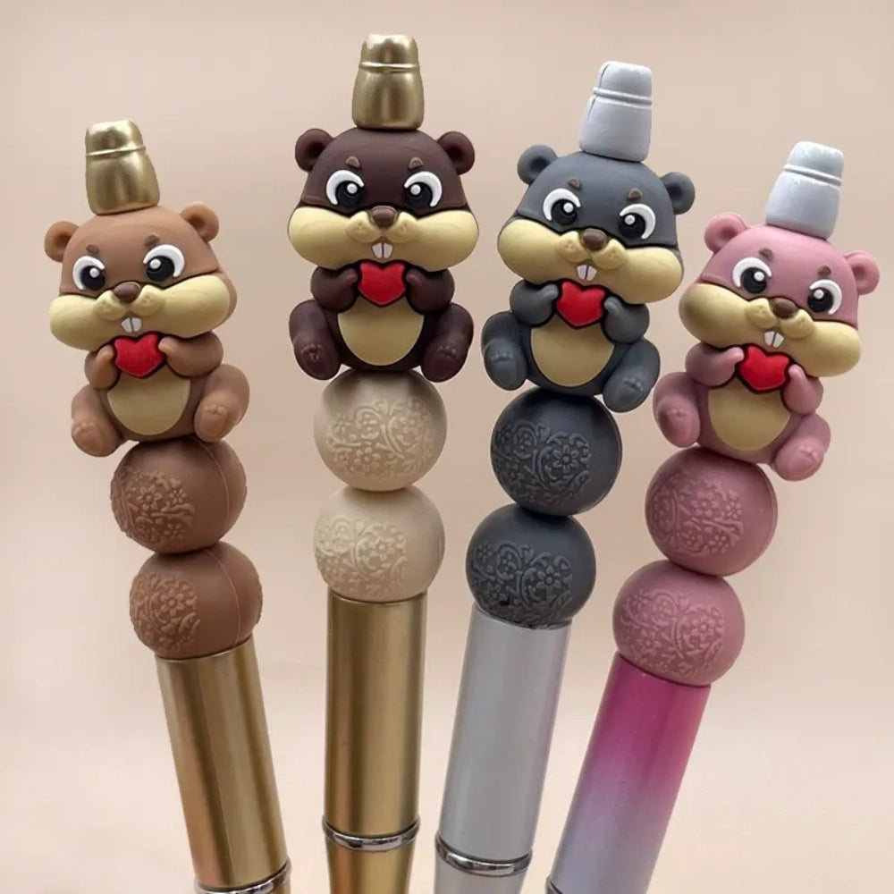 Four 3D silicone focal beads shaped like cute beavers holding red hearts in brown, dark brown, gray, and pink colors, displayed on matching beadable pens with decorative floral silicone beads.