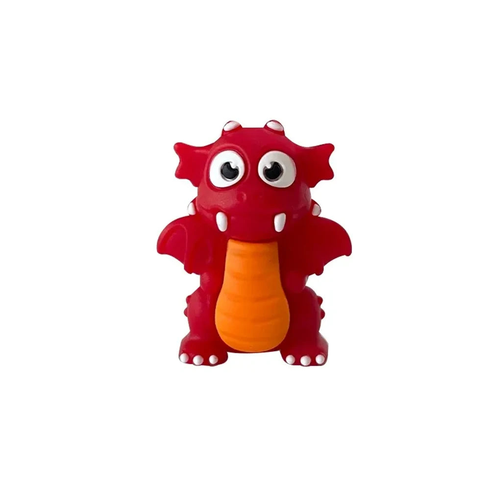 Set of seven 3D cartoon dragon silicone focal beads in black, lime green, dark green, and red colors displayed on and around a miniature white wooden bench against a light green background. - Red