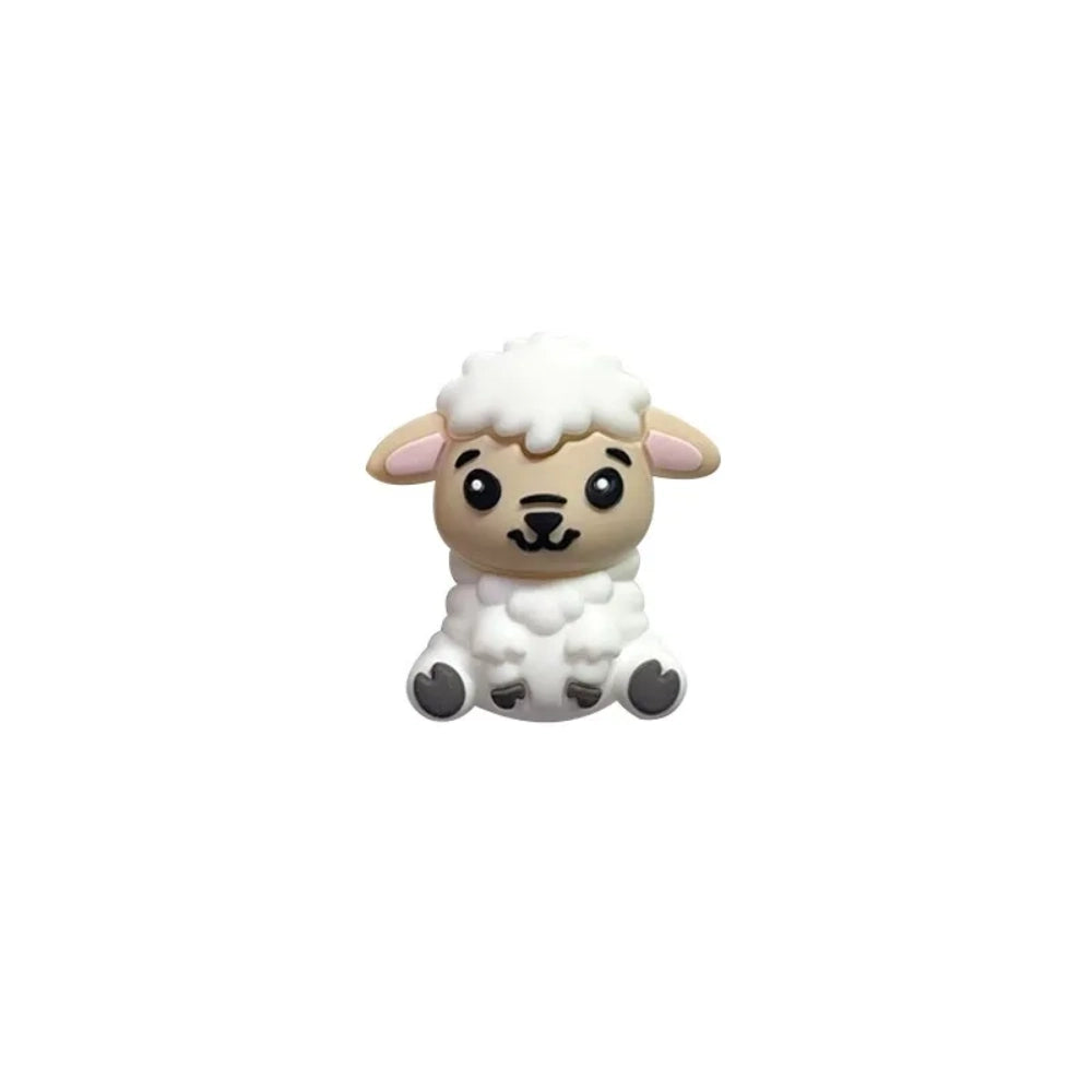 Six miniature 3D silicone focal beads shaped like cute sitting lambs in brown, tan, grey, and white colorways displayed on a white platform with pink flowers on a mauve background. - White