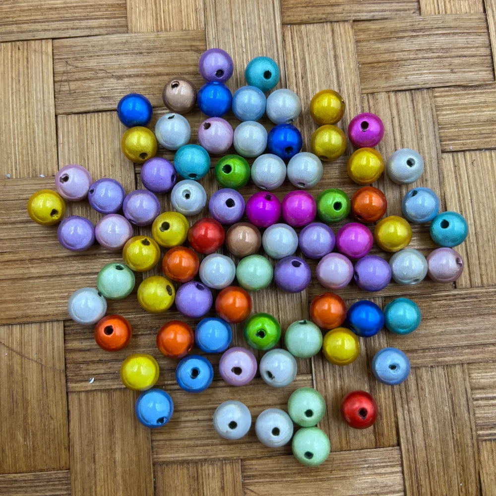 8MM mixed color miracle acrylic beads in assorted rainbow colors including pink, blue, yellow, purple, orange, green and teal scattered on a woven bamboo surface, showing glossy 3D illusion finish with drilled holes for jewelry making and beadable pens.