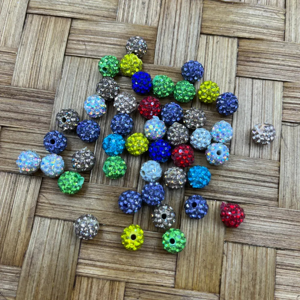 8MM mixed color rhinestone disco ball beads in assorted colors including blue, red, green, yellow, gray, and iridescent AB finish, scattered on a woven bamboo surface.