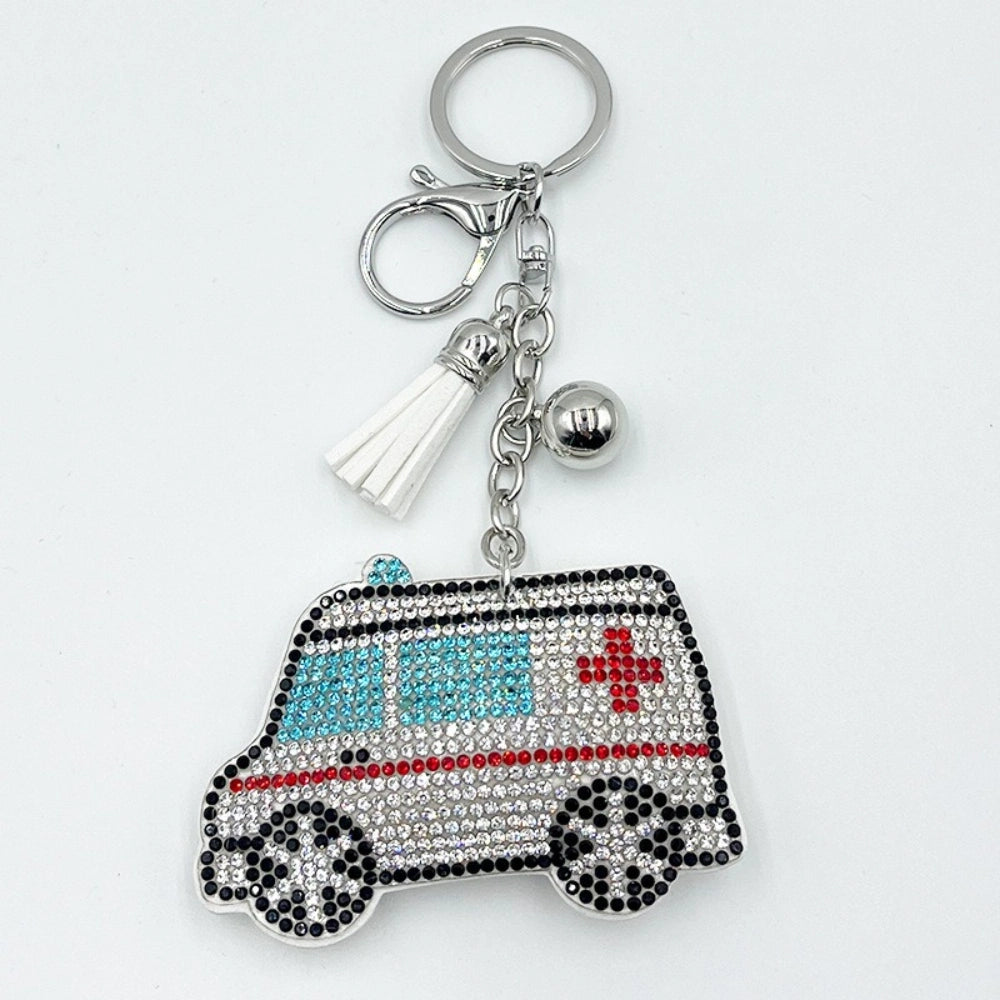 Rhinestone bling ambulance keychain charm with white tassel and silver ball, decorated with clear, black, red, and blue crystals forming an ambulance design with red cross.