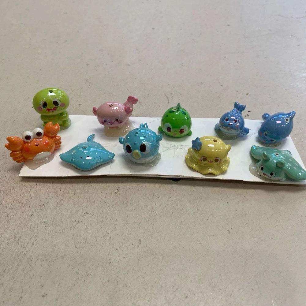 Assorted cartoon ocean animal silicone straw toppers in pastel colors, including crab, stingray, whale, octopus, and fish designs