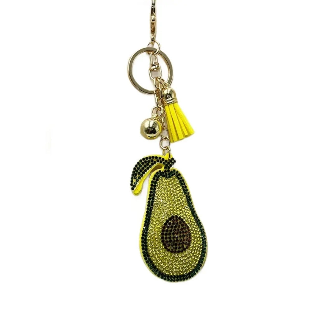 Sparkling avocado-shaped rhinestone keychain charm with yellow tassel, gold bell, and lobster clasp on white background.