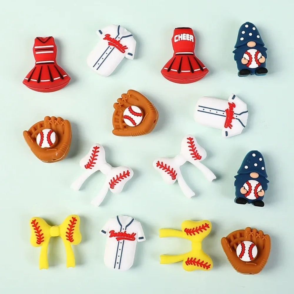 Assorted baseball themed silicone focal beads including baseball gloves, jerseys, cheerleader uniforms, bow ties, and gnome characters in red, white, blue, and yellow on a mint background.