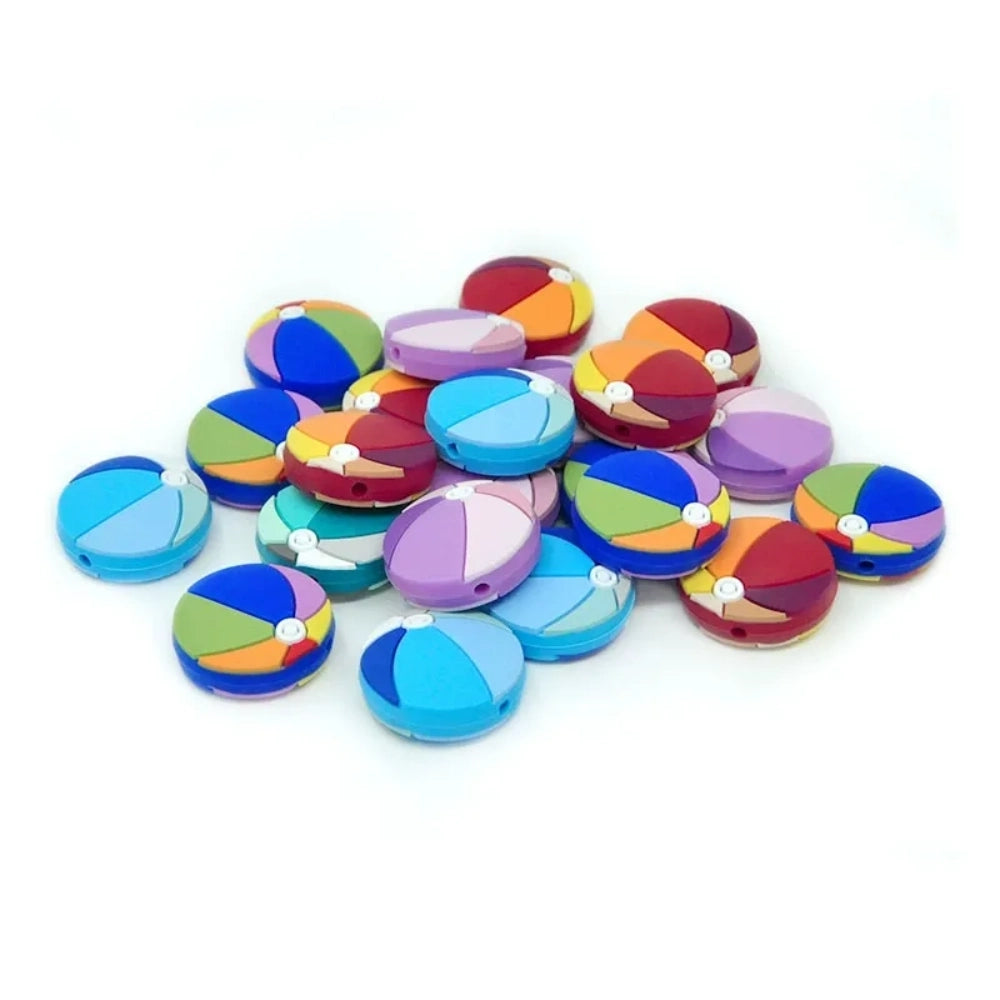 Colorful beach ball silicone focal beads in assorted multicolor designs including blue, red, purple, and teal panels with white center detail, shown in a pile on white background.