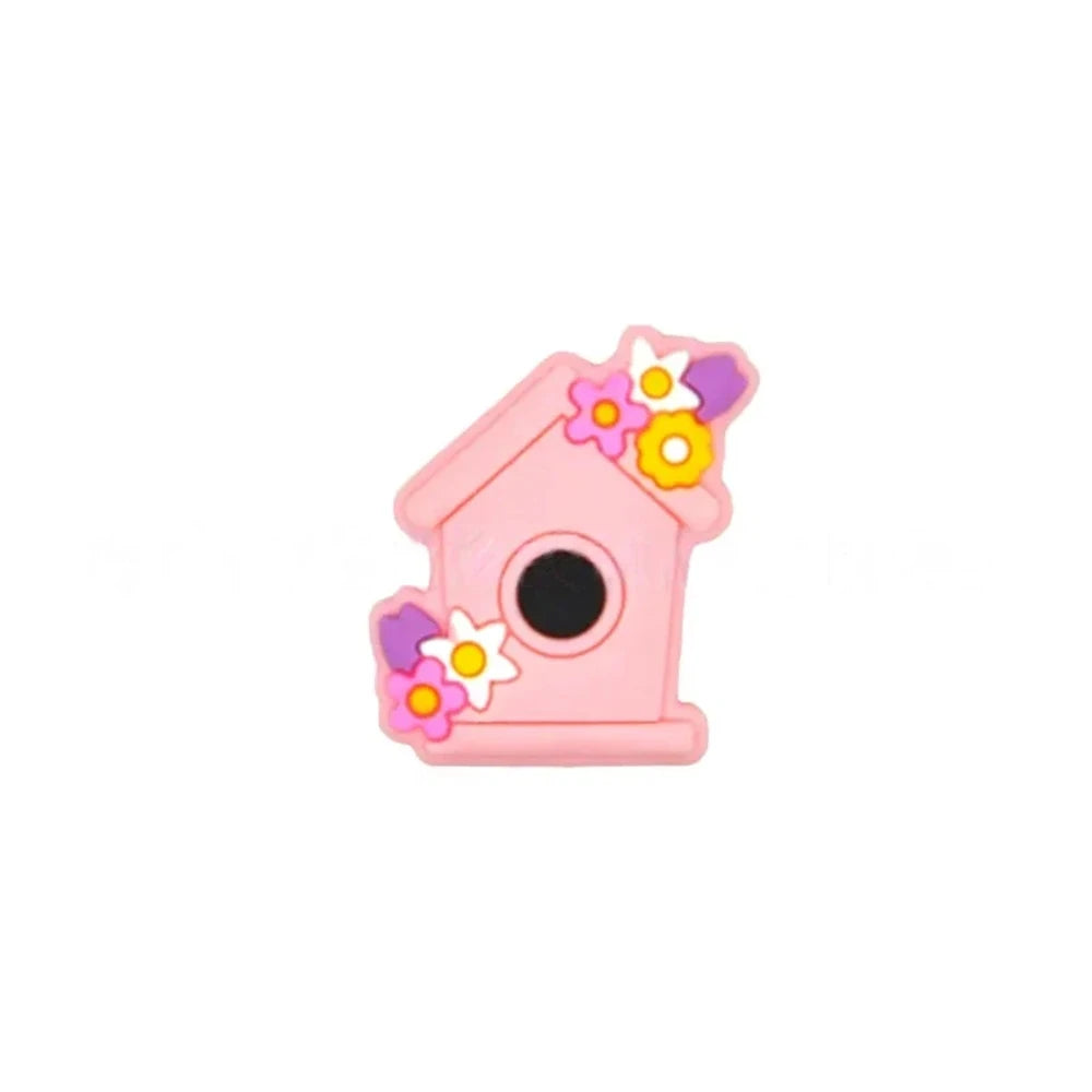 Six pastel silicone focal beads shaped like birdhouses decorated with flowers in pink, lavender, yellow, teal, mint, and blue colors displayed on a miniature white bench. - Candy Pink
