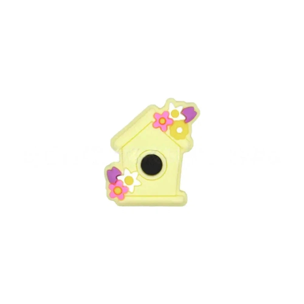 Six pastel silicone focal beads shaped like birdhouses decorated with flowers in pink, lavender, yellow, teal, mint, and blue colors displayed on a miniature white bench. - Creamy Yellow