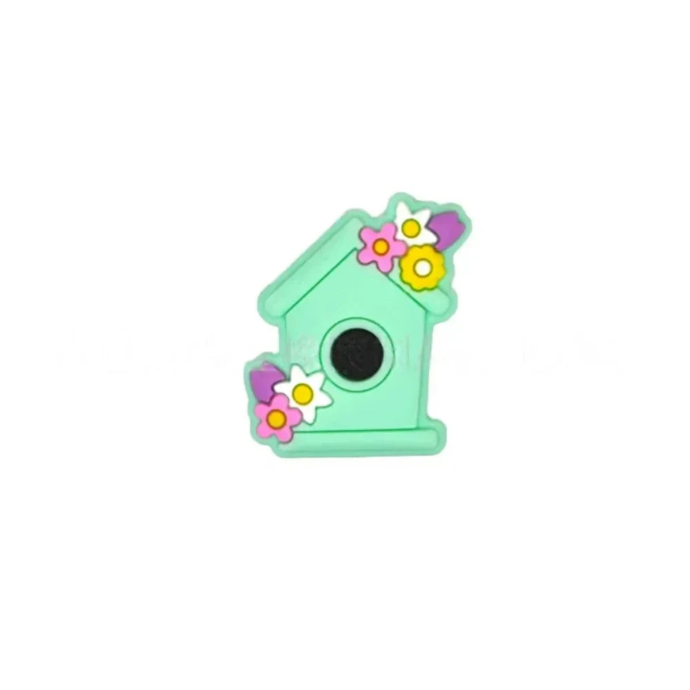 Six pastel silicone focal beads shaped like birdhouses decorated with flowers in pink, lavender, yellow, teal, mint, and blue colors displayed on a miniature white bench. - Mint Green