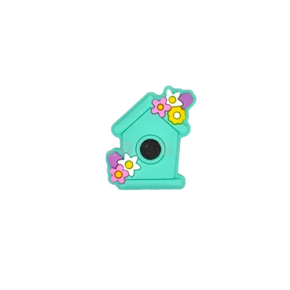 Six pastel silicone focal beads shaped like birdhouses decorated with flowers in pink, lavender, yellow, teal, mint, and blue colors displayed on a miniature white bench. - Turquoise